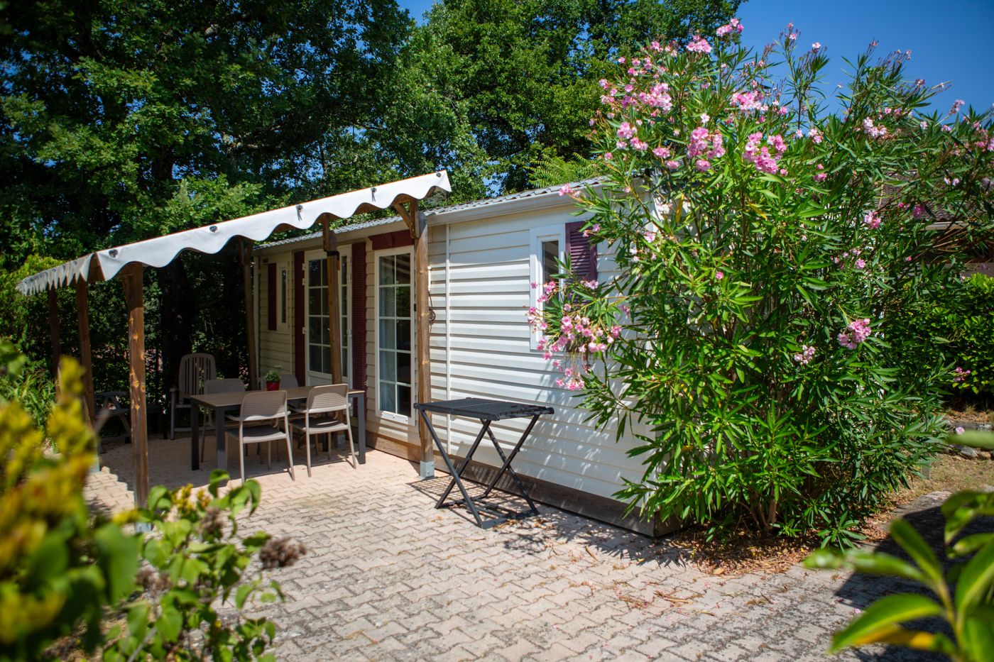 Mobile home met overkapt terras tussen de bloemen